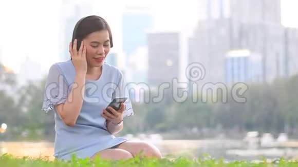 年轻的亚洲女性通过听无线耳机音乐来享受电梯式视频的预览图