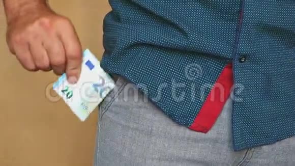 一个男人把欧元钞票放进裤兜里一个人把钱藏在口袋里视频的预览图