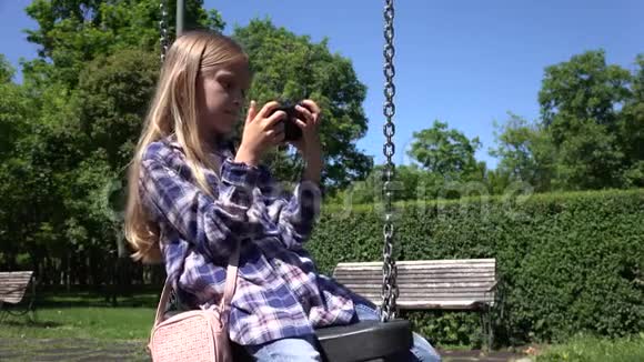 儿童摇摆游戏桌儿童户外公园女孩摇摆使用智能手机视频的预览图