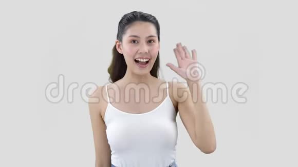 穿着白色上衣的黑头发的漂亮女人微笑着用左手挥手视频的预览图