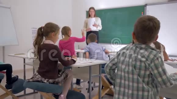 初中时快乐的孩子们从课桌上起来下课后跑到女老师身边拥抱她视频的预览图