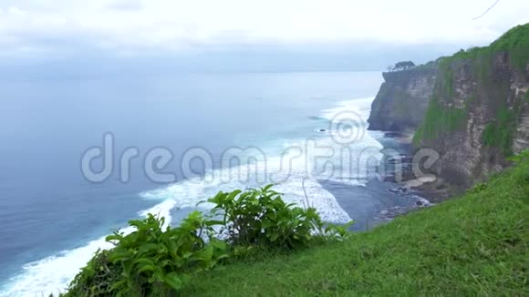 山崖上的海洋海岸和水波上的天际线景观高山峭壁覆盖着热带植物视频的预览图