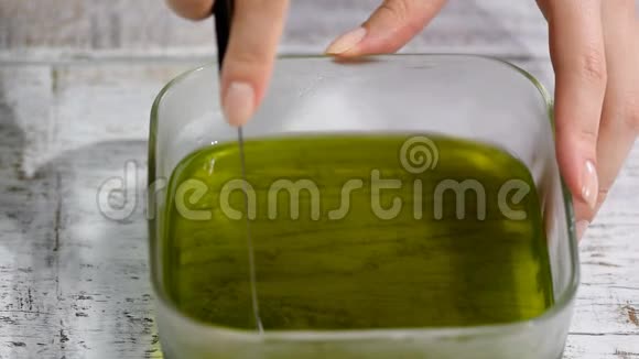 女性手把绿色果冻切成碎片视频的预览图