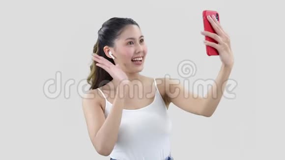 东方年轻女子用红色智能手机打视频电话穿着普通上衣视频的预览图