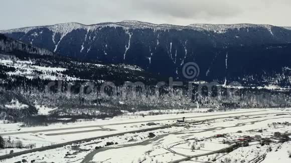 惊人的空中镜头山上覆盖着雪和一个小村庄附近4k视频的预览图