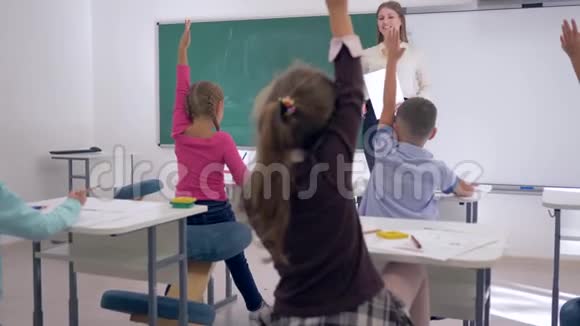 孩子们在学校里孩子们举手回答老师的问题女学生上黑板写简单的字视频的预览图