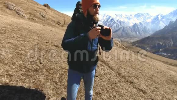 一位留胡子的快乐旅行者摄影师戴着太阳镜和帽子手里拿着反射相机拍摄的肖像视频的预览图
