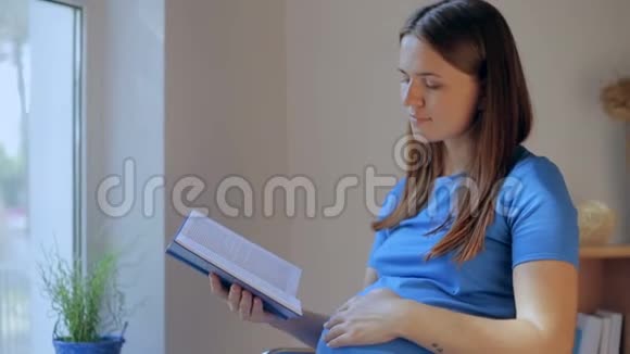 坐在沙发上的惊讶孕妇边看书边看视频的预览图