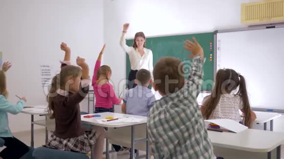 老师站在教室前面靠近黑板向学生们提问他们是向谁举手的视频的预览图