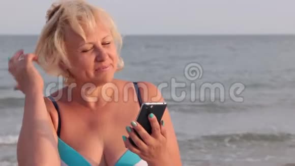幸福的女人在海浪的背景下用电话在网上交流视频的预览图