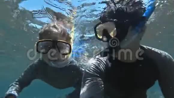 与父亲一起在清澈湛蓝的海水中带着鱼潜泳的孩子视频的预览图