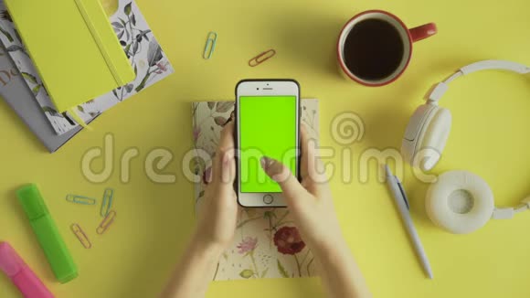 双手顶视女人用她的智能手机桌子上有绿色屏幕滚动新闻照片办公室背景视频的预览图