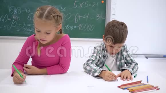 私立学校孩子们坐在教室的书桌前在白纸上画彩色记号视频的预览图