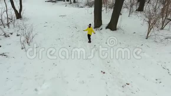 穿黄色外套跳绳在冬林中跳跃的大胡子男子视频的预览图