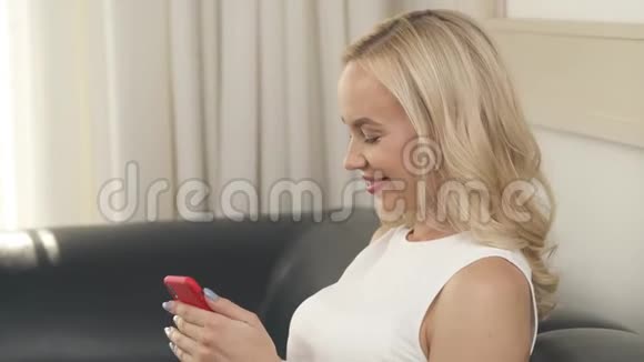 坐在沙发上滚动手机的孕妇侧视画像她正在看信息视频的预览图