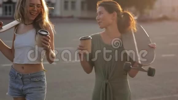两个少女朋友在阳光下玩滑板在欧洲街镇嘲笑外面的东西的肖像视频的预览图