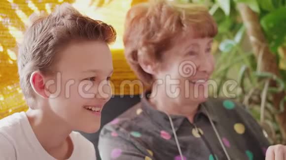 年长妇女和少年男孩微笑着看着展示视频的预览图