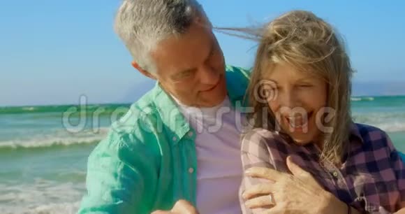 活跃的高加索夫妇在海滩上用手机自拍的正面景色视频的预览图