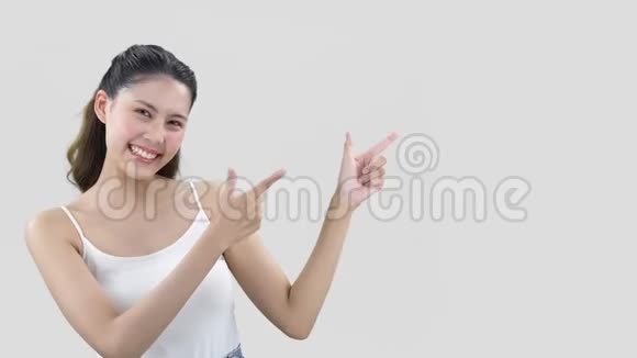 幸福的年轻笑容满面的黑发女人指着一边穿着白色的细绳背心视频的预览图