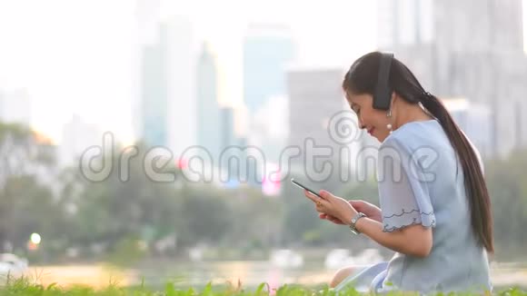 年轻的亚洲女性通过听无线耳机音乐来享受电梯式视频的预览图