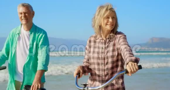活跃的高加索夫妇在海滩上骑自行车站立的正面景色视频的预览图
