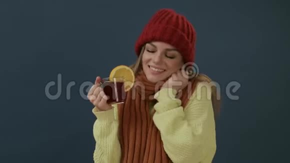 戴着围巾戴着帽子喝着热茶喝着橘红色的酒的漂亮年轻女子视频的预览图