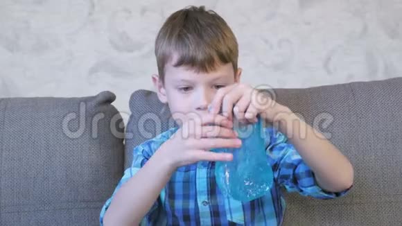 快乐的男孩正在伸展一个蓝色的黏液坐在教练上玩从黏液里看过去视频的预览图