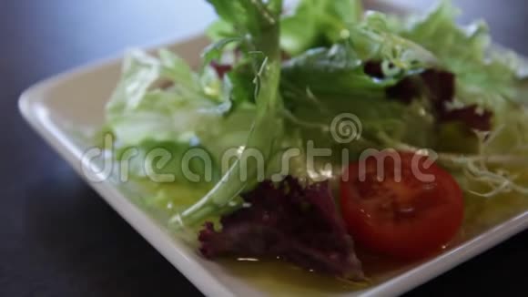 方形白色盘子配绿色生菜西红柿和橄榄油视频的预览图