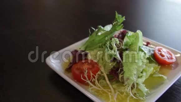 方形白色盘子配绿色生菜西红柿和橄榄油视频的预览图
