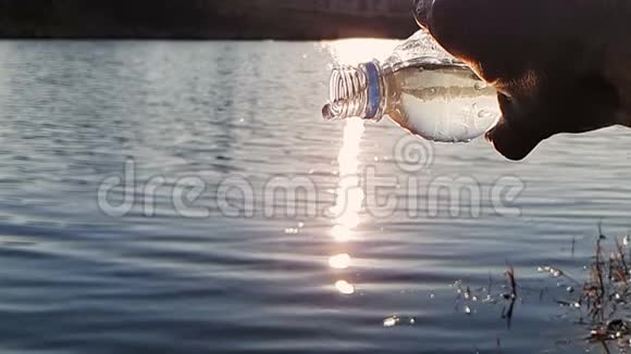 特写水从一个塑料瓶里流出在阳光明媚的一天靠在湖边太阳在今天形成了眩光视频的预览图