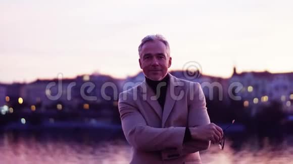 一个成熟的商人在黄昏时站在布拉格的一座桥上视频的预览图
