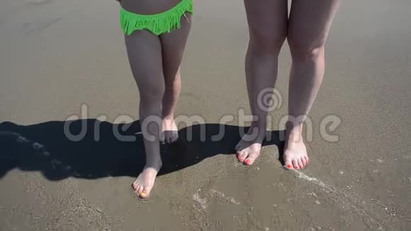 沙滩上妇女和女童的腿被海浪冲走视频的预览图