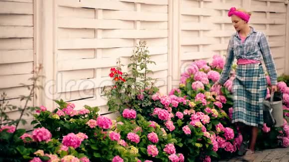在美丽的花园里浇花的女人快乐而微笑的女人关心花园里的植物概念视频的预览图