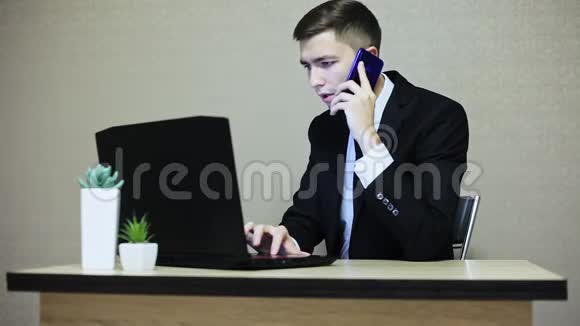 商人在办公室工作用手提电脑打字用手机说话视频的预览图