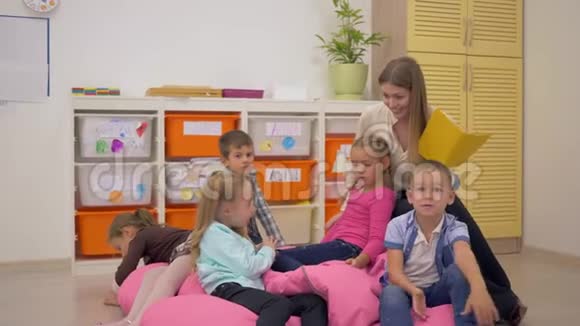 友好的女老师坐在豆包椅上在学校的教室里和孩子们聊天视频的预览图