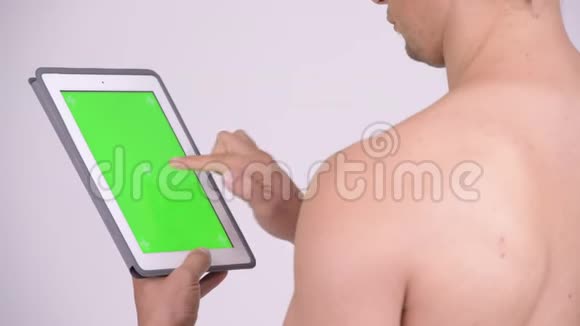使用数码平板电脑近距离观看肌肉无衬衫男士视频的预览图