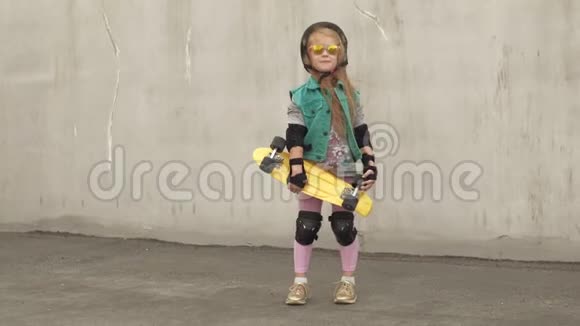 一个快乐的小女孩站在那里手里拿着黄色的冰鞋微笑着视频的预览图