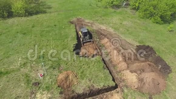 小型装载机和挖掘机在草地上挖基坑视频的预览图