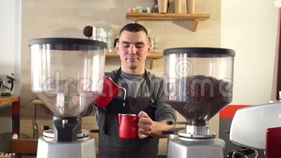 一位男咖啡师在一家现代化的咖啡店工作他把牛奶倒进一杯咖啡里视频的预览图
