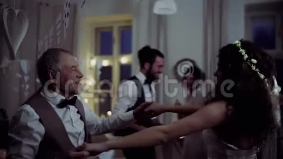 在婚宴上与祖父和其他客人跳舞的年轻新娘视频的预览图
