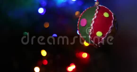 猫在云杉树枝上玩圣诞软玩具背景是多种颜色的圣诞彩灯花环视频的预览图