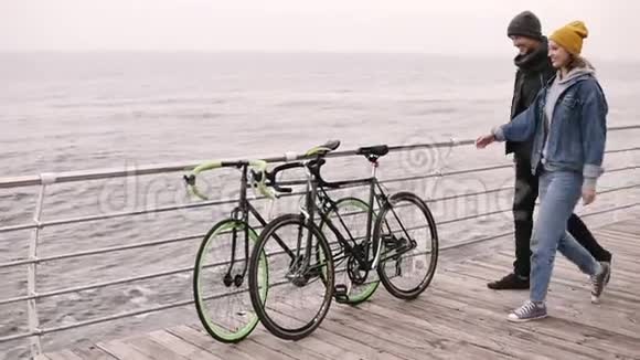 在秋天一对年轻的嬉皮士开始和他们的自行车一起在海边散步走过去视频的预览图