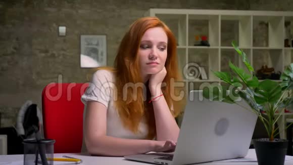 一个可爱体贴红发白种人的女人坐在电脑前微笑着写着笔记视频的预览图