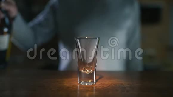关闭慢镜头下向玻璃杯中倒入深色白酒的视频在酒吧中倒入酒精在工作时调酒师4kUHD视频的预览图