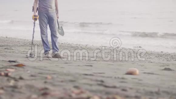人们在沙滩上寻找贵重物品在日出时使用金属探测器双腿特写视频的预览图
