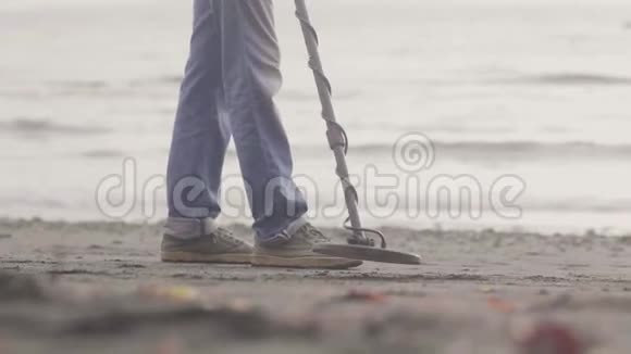 人们正在海滩上工作手持金属探测器在日出时在海岸线上的沙滩上发现金属视频的预览图