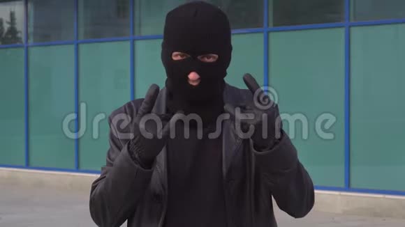 罪犯小偷或戴面具的强盗在镜头前显示角的标志视频的预览图