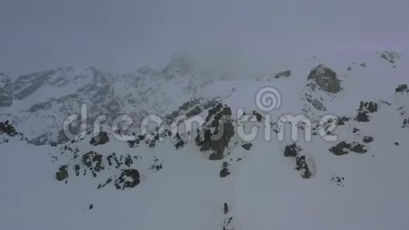 暴风雪在山上雾覆盖了岩石山空中拍摄4k视频的预览图