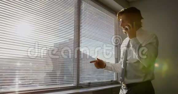 年轻的高加索男性高管在现代办公室靠近窗户的手机上交谈的侧视图视频的预览图