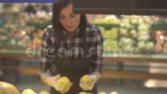 年轻的女店员穿着棕色围裙在新鲜的柑橘类水果橘子和柠檬中打着一种视频的预览图